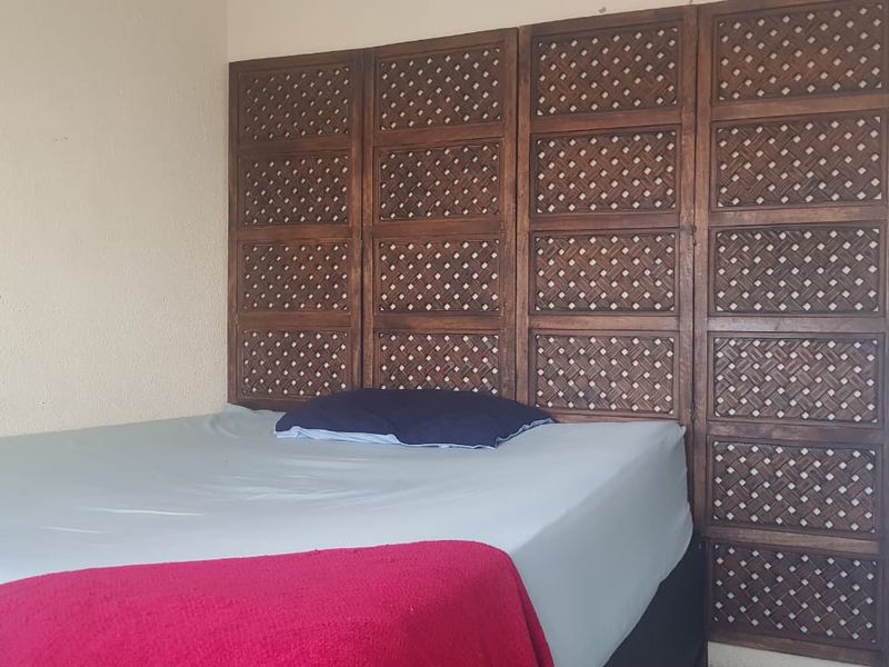 A bedroom featuring a large, decorative wooden lattice wall panel behind the bed area.