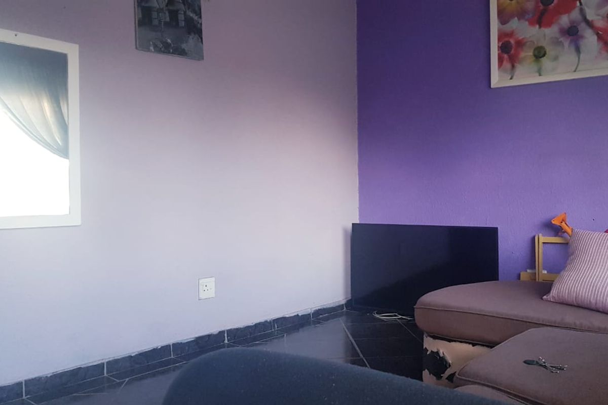 A living room area featuring tiled flooring and painted walls, currently furnished with a sofa.