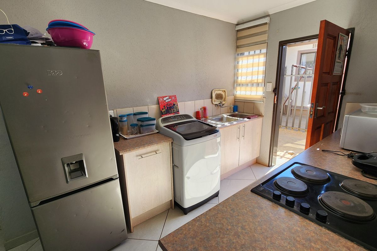 Functional kitchen featuring built-in cabinetry, laminate countertops, an electric hob, and direct access to an outdoor area.