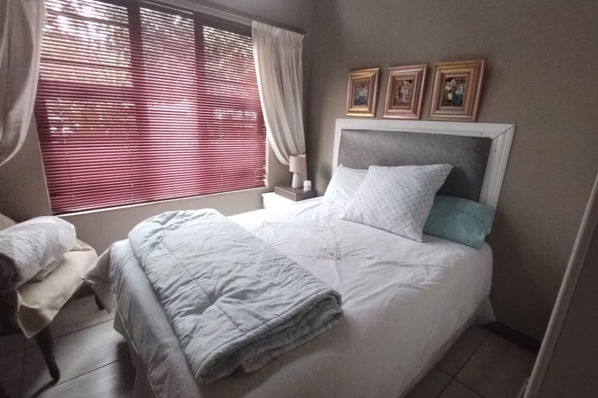 A cozy bedroom featuring tiled flooring and venetian blinds, providing a functional and comfortable sleeping space.