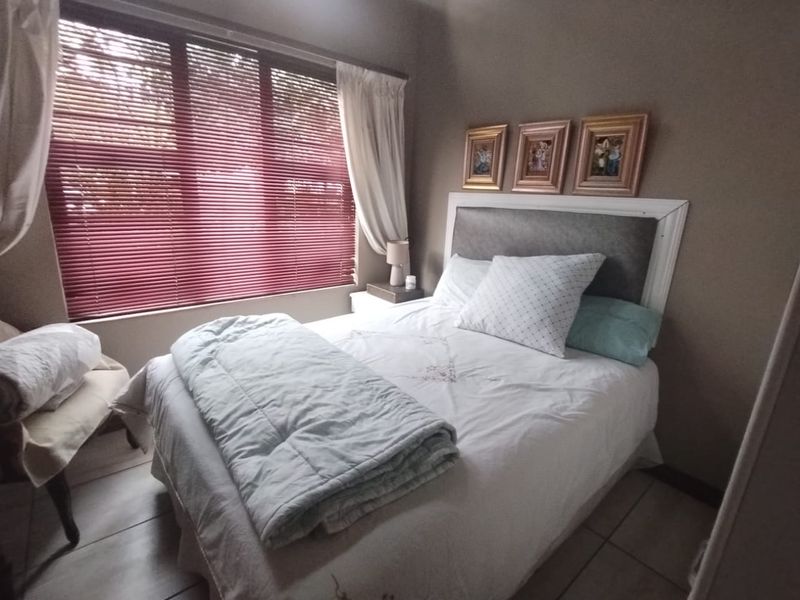 A cozy bedroom featuring tiled flooring and venetian blinds, providing a functional and comfortable sleeping space.