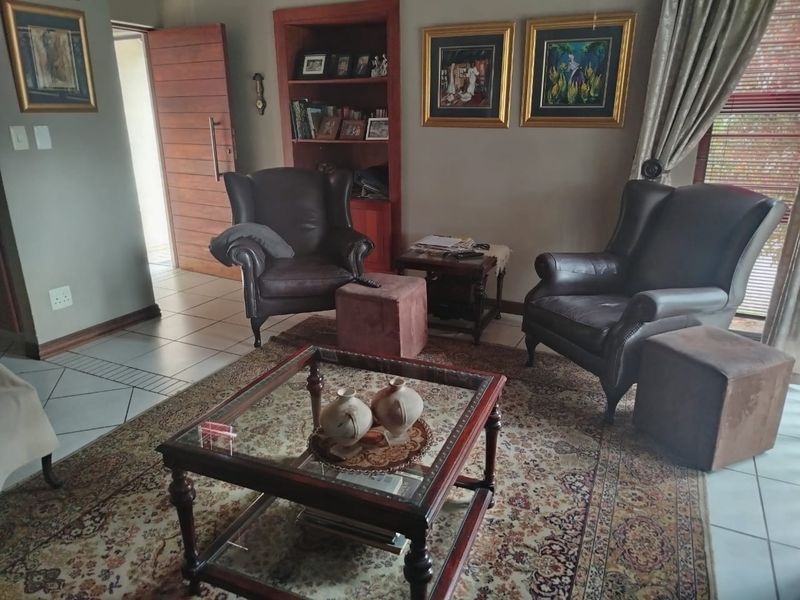 A comfortable living room featuring tiled flooring, a built-in wooden bookshelf, and a solid wood entrance door.