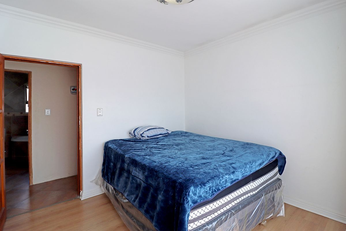 A simple bedroom featuring laminate flooring and a doorway leading to an adjacent bathroom.