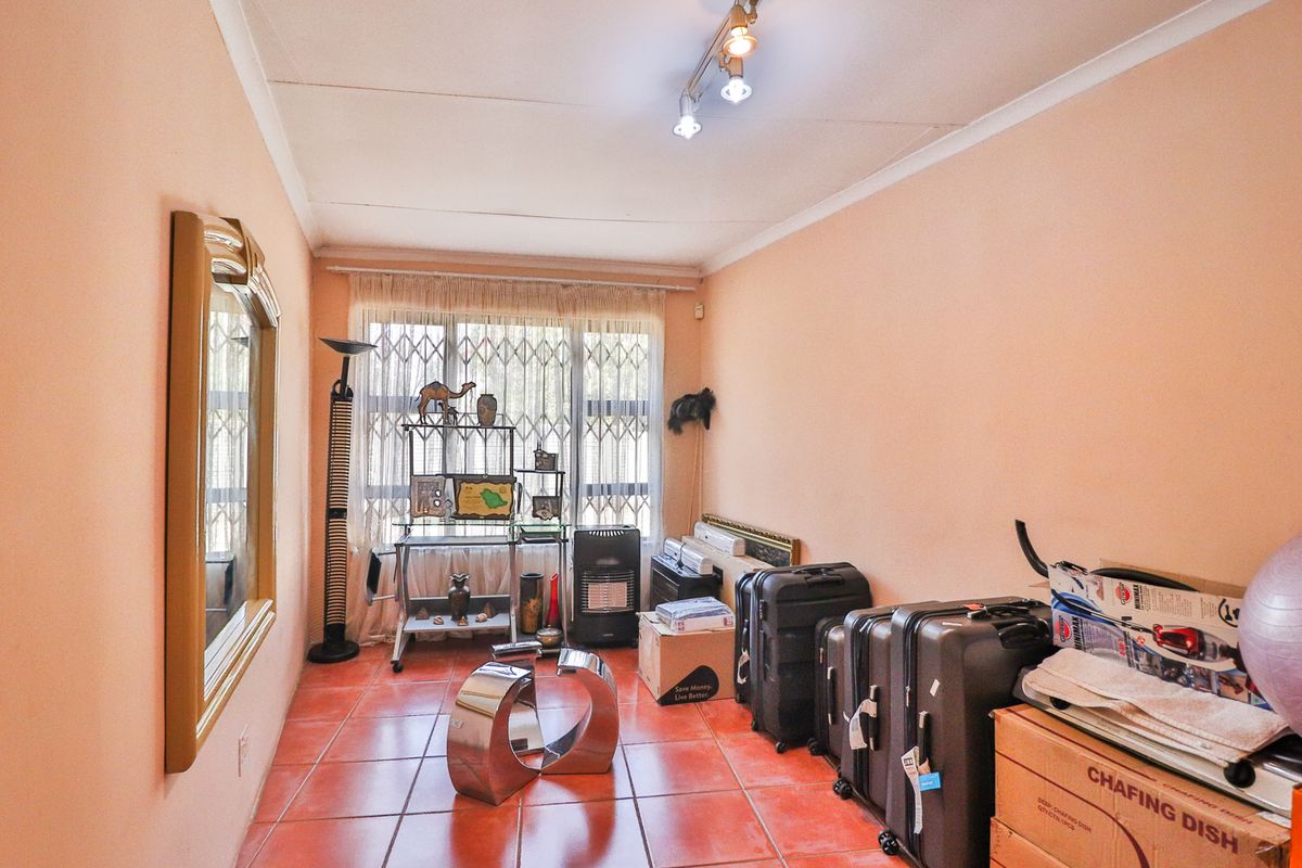 A bedroom featuring tiled flooring, a security gate on the window, and ceiling-mounted spotlighting.