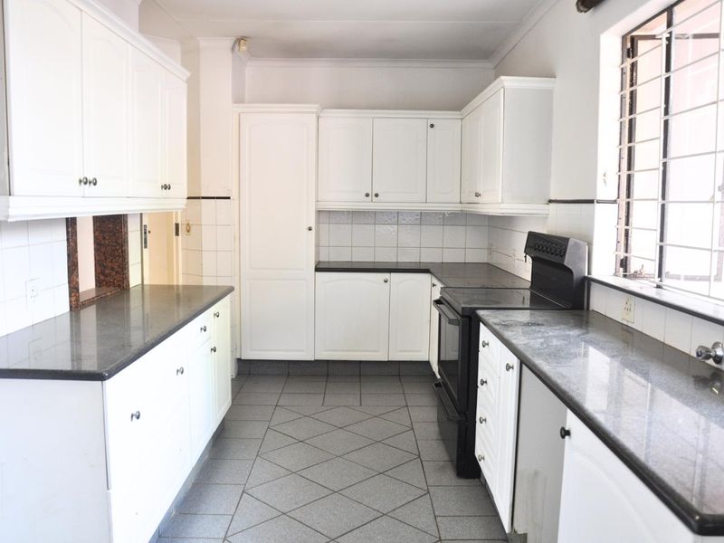 A functional kitchen featuring white cabinetry, dark granite countertops, tiled flooring, and a built-in stove with an integrated oven.