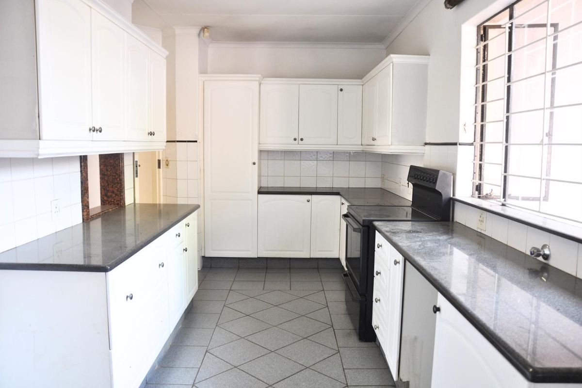 A functional kitchen featuring white cabinetry, dark granite countertops, tiled flooring, and a built-in stove with an integrated oven.