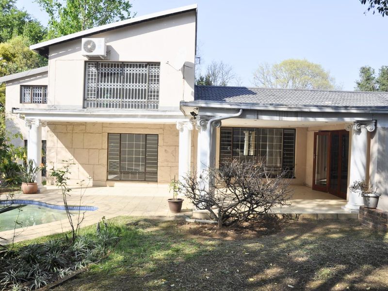 Rear view of a two-story house featuring a covered patio, swimming pool, and classic column architectural details.