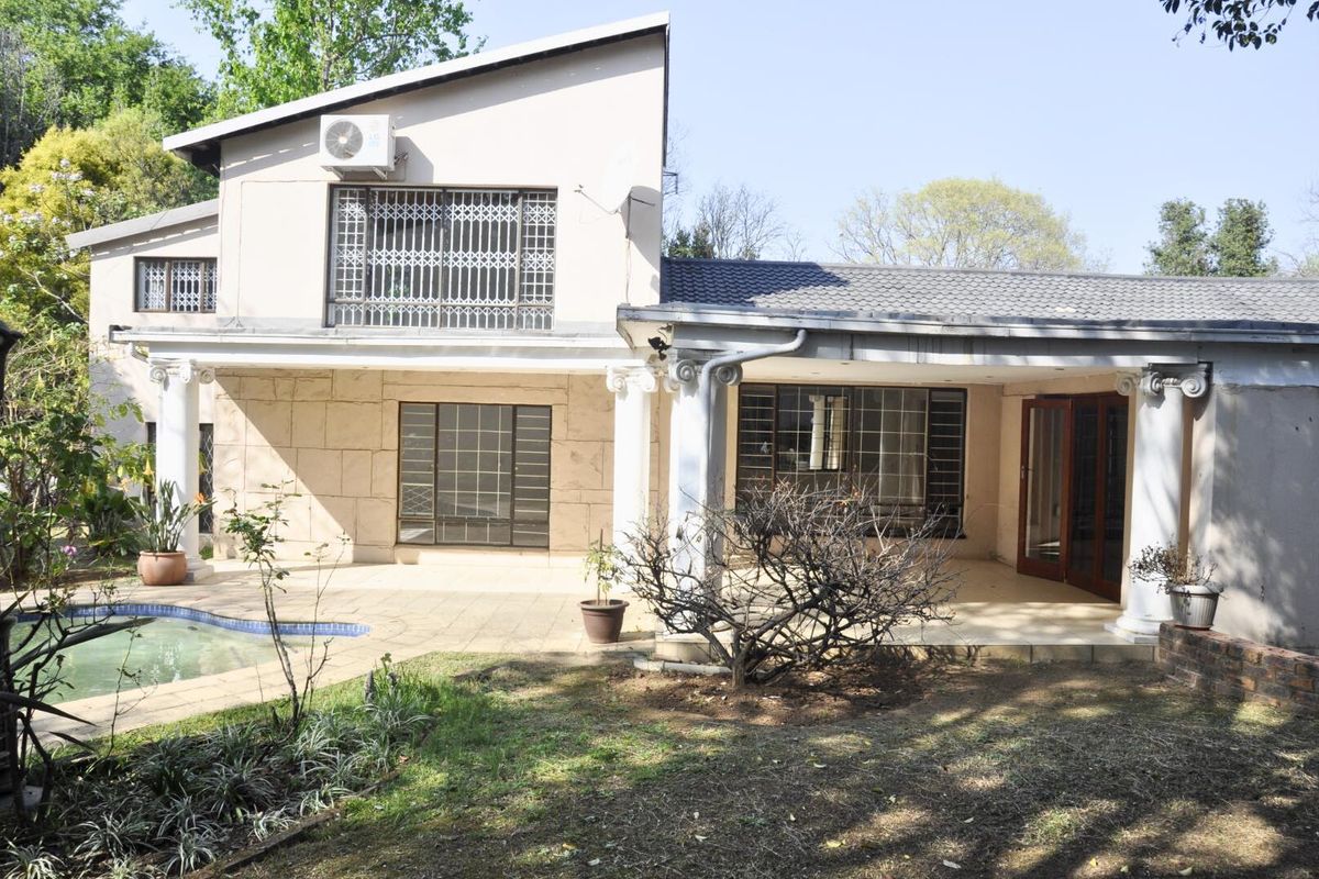 Rear view of a two-story house featuring a covered patio, swimming pool, and classic column architectural details.