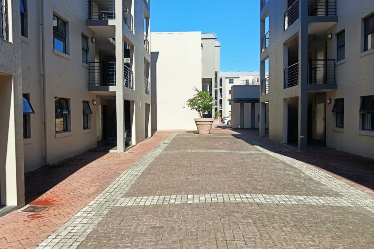 A view of the paved courtyard between apartment blocks, featuring multi-level balconies and external access staircases.
