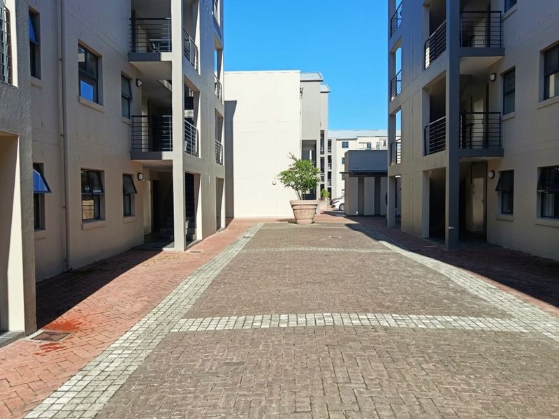 A view of the paved courtyard between apartment blocks, featuring multi-level balconies and external access staircases.