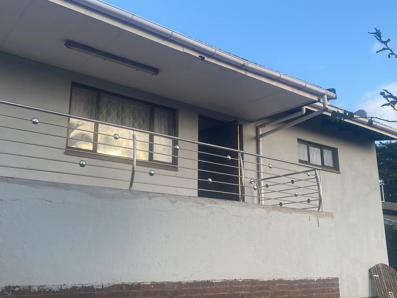 Elevated balcony area featuring a modern stainless steel balustrade and access to the main dwelling entrance.