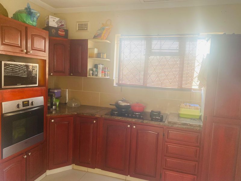 A functional kitchen featuring dark wood cabinetry, granite countertops, a built-in oven, and a gas hob with a tiled backsplash.
