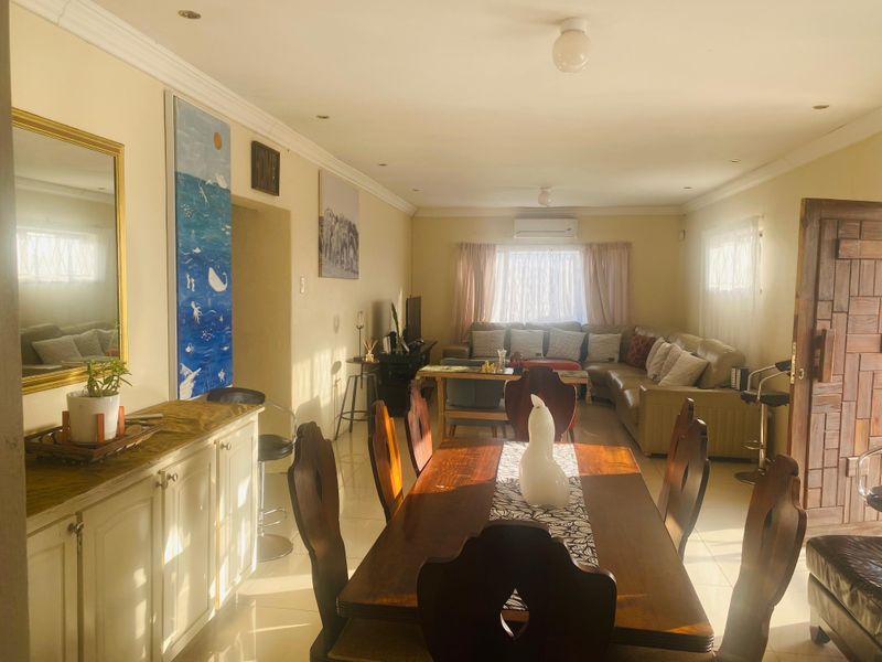 Spacious open-plan living and dining area featuring tiled floors, recessed lighting, and a wall-mounted air conditioning unit.