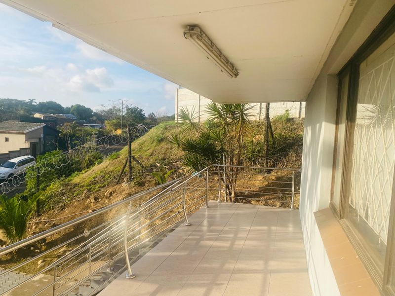 A covered balcony featuring tiled flooring and a modern stainless steel balustrade, offering an elevated view of the surrounding area.
