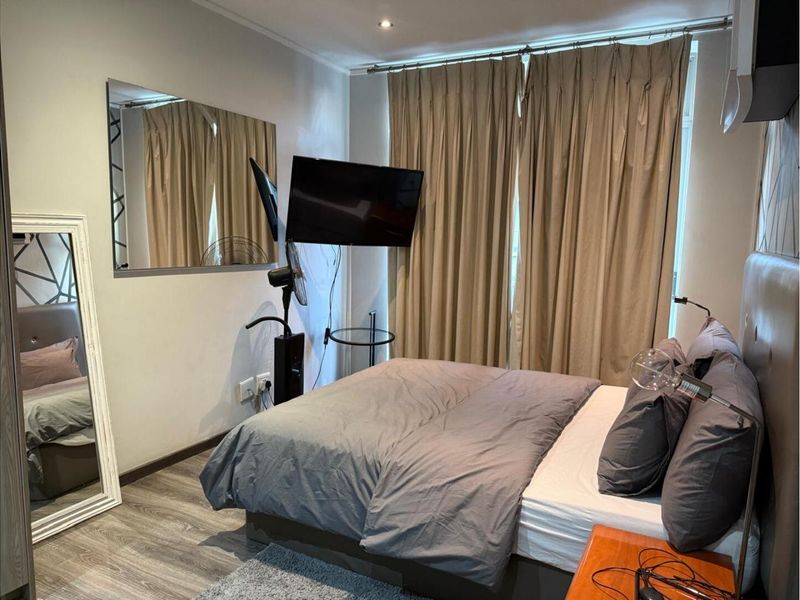 A well-maintained bedroom featuring wood-look laminate flooring, recessed ceiling lighting, and neutral wall finishes, providing a comfortable and functional living space.