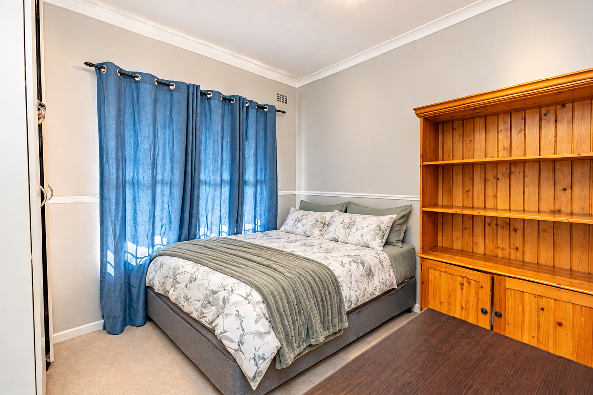 A well-maintained bedroom featuring neutral wall tones, classic chair rail molding, coving, and a functional built-in wardrobe.