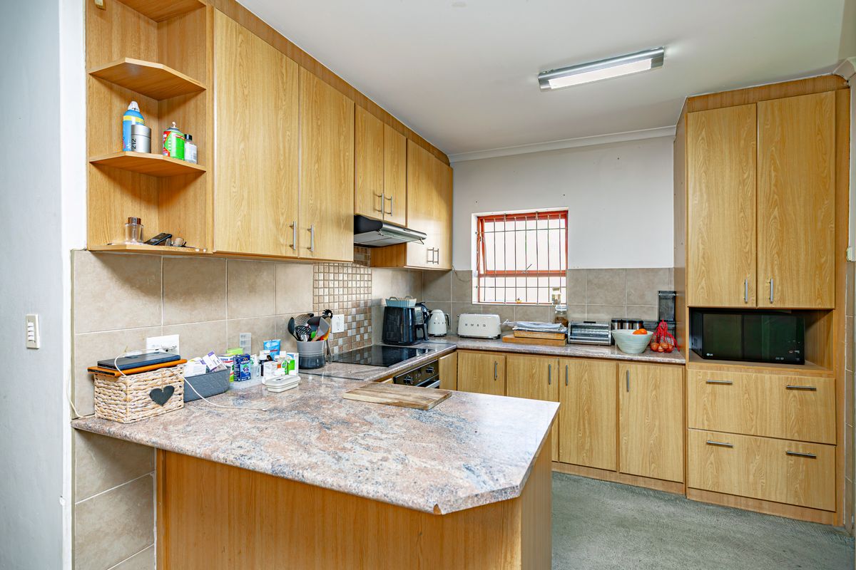 A functional kitchen featuring wood-look laminate cabinetry, granite countertops, a tiled backsplash, and built-in cooking appliances.