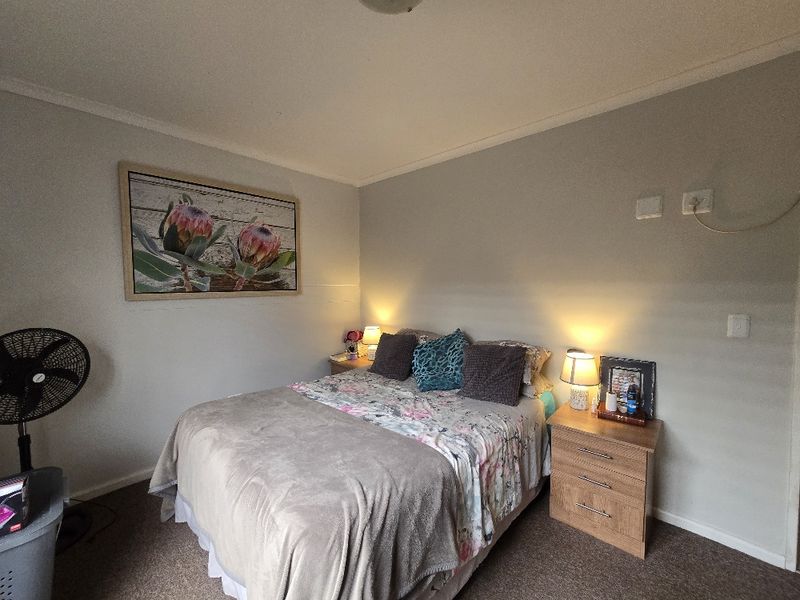 A cozy bedroom featuring neutral wall tones, carpeted flooring, and coved ceiling details, providing a comfortable and functional sleeping space.