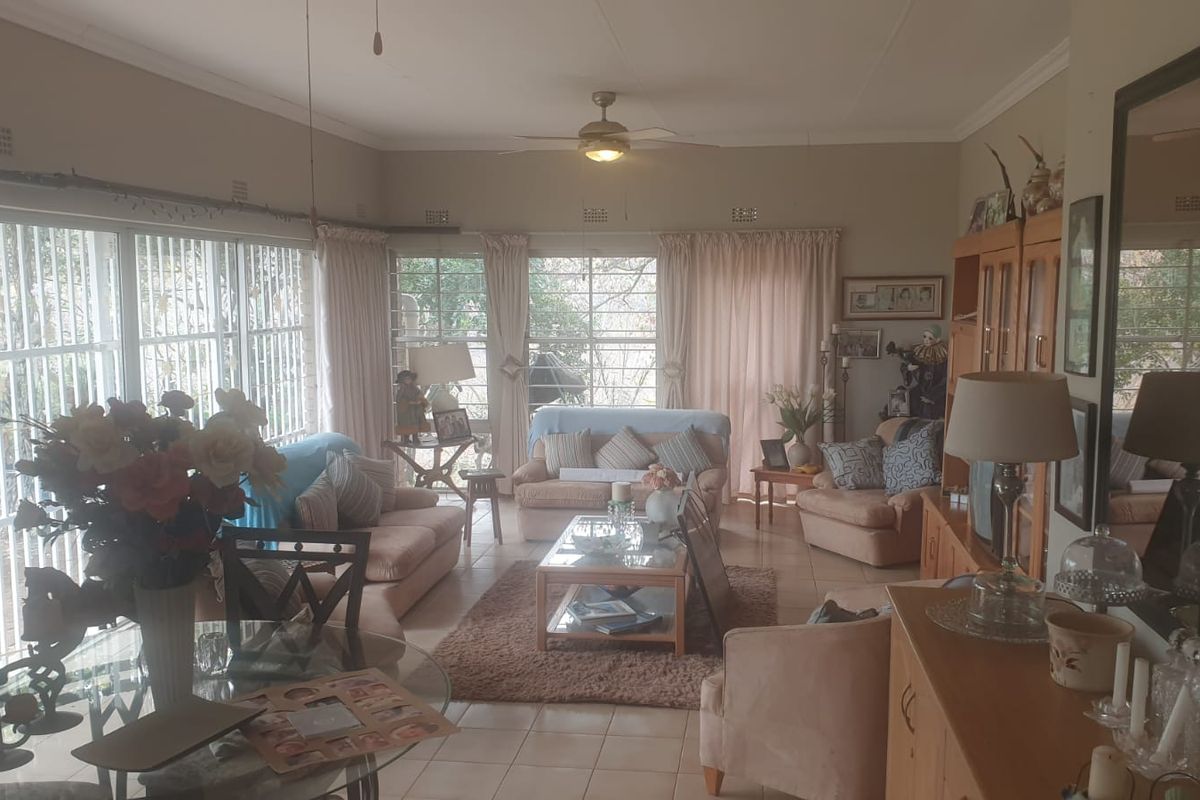 Spacious living room featuring tiled flooring, a ceiling fan, and large sliding glass doors with security bars, providing ample natural light.