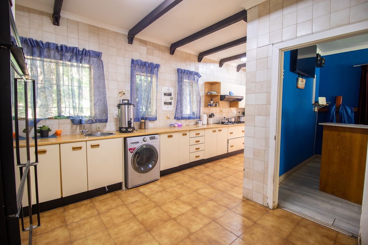 A functional kitchen featuring extensive built-in cabinetry, laminate countertops, and exposed ceiling beams, offering a dated aesthetic ready for modernization.