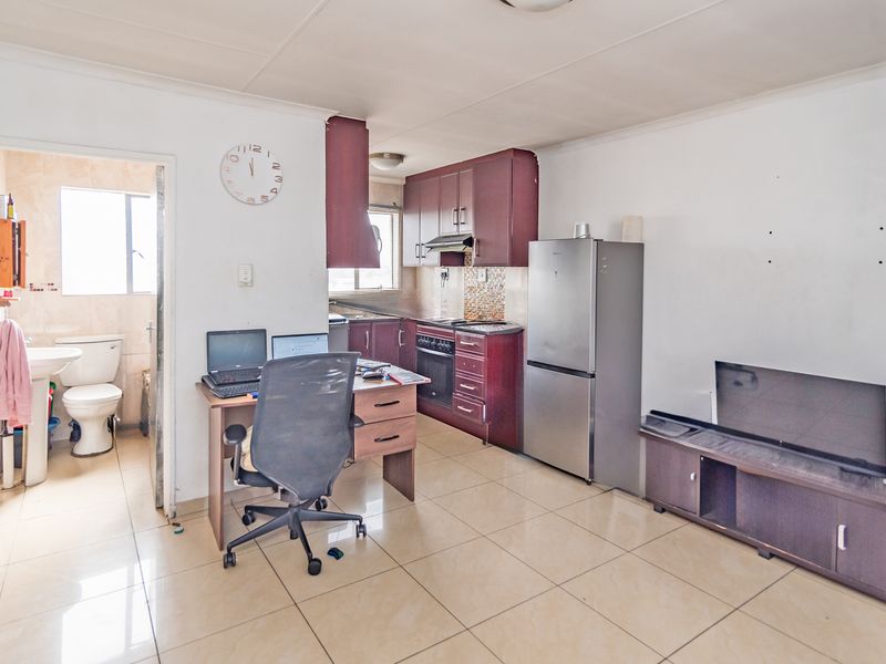 Open-plan living area featuring a compact kitchen with built-in cabinetry and an adjacent bathroom with a pedestal basin and toilet.
