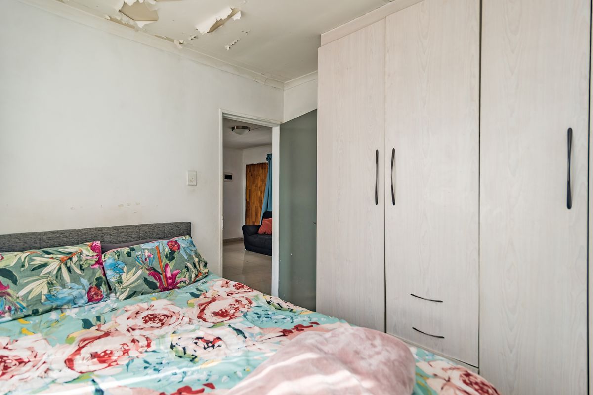 Bedroom featuring a built-in wardrobe and requiring ceiling repairs due to peeling paint.