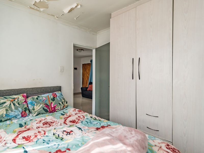 Bedroom featuring a built-in wardrobe and requiring ceiling repairs due to peeling paint.