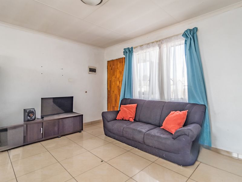 A living room featuring tiled flooring and coved ceilings, offering a functional space ready for cosmetic updates and personalization.