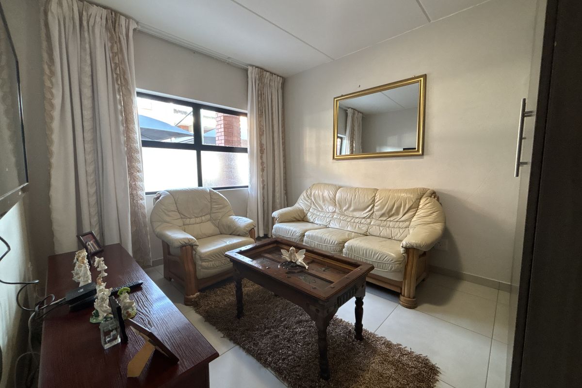 A compact living room featuring tiled flooring and a large window, providing a functional space for relaxation.