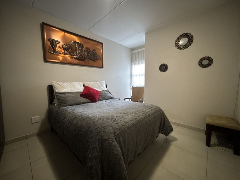A bedroom featuring neutral wall finishes and tiled flooring, providing a functional and well-lit sleeping space.