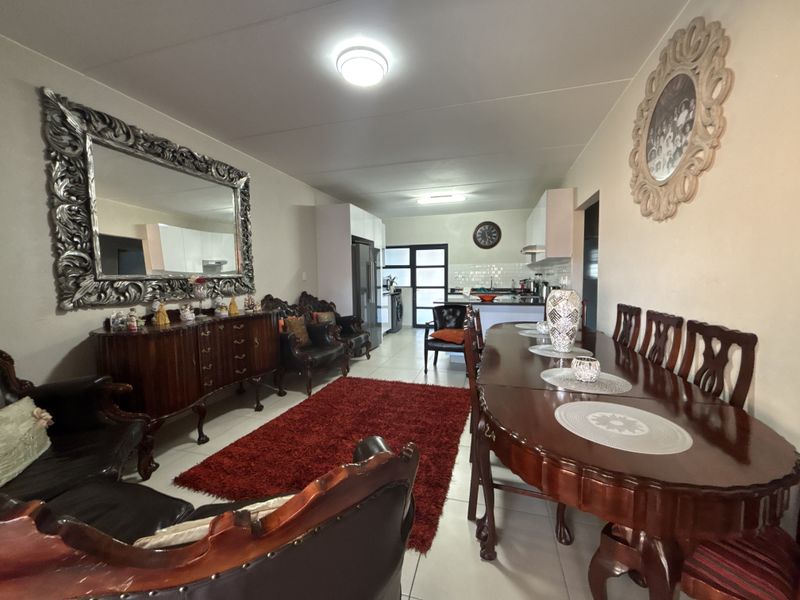 Spacious open-plan living and dining area flowing into a functional kitchen with tiled flooring and modern cabinetry.