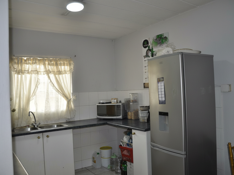 A functional kitchen area featuring laminate countertops, a stainless steel sink, and tiled splashbacks, providing a practical workspace for daily meal preparation.