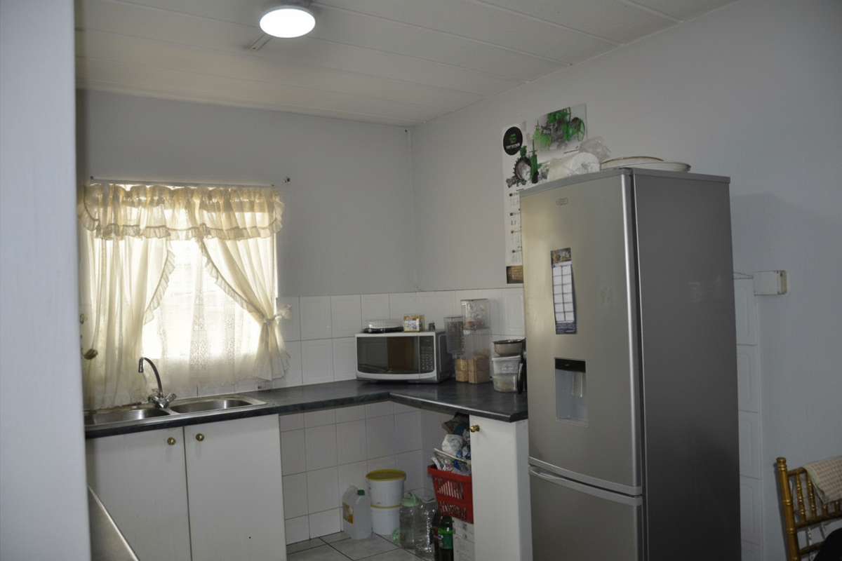 A functional kitchen area featuring laminate countertops, a stainless steel sink, and tiled splashbacks, providing a practical workspace for daily meal preparation.