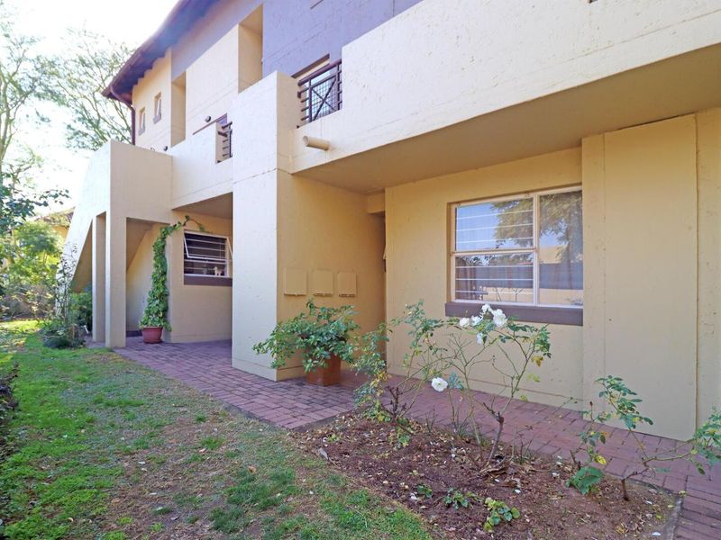 Rear exterior view of the townhouse featuring a paved patio area, garden space, and access to the ground floor living area.