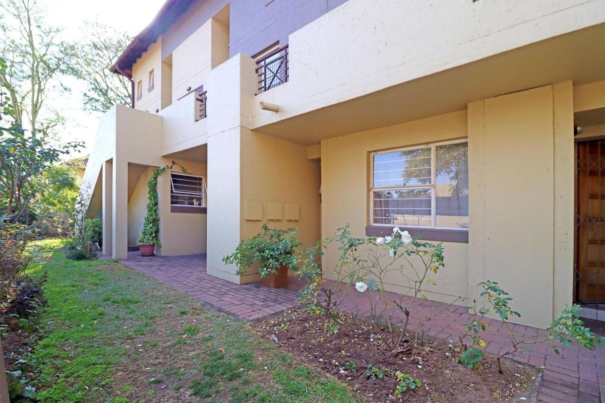 Rear exterior view of the townhouse featuring a paved patio area, garden space, and access to the ground floor living area.