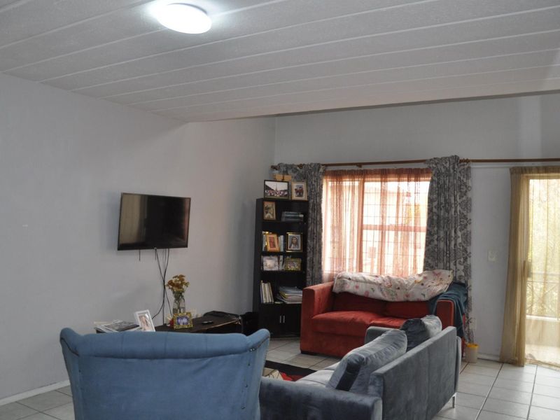 A living room featuring tiled flooring, a ceiling with paneling, and a glass door providing access to an outdoor area.