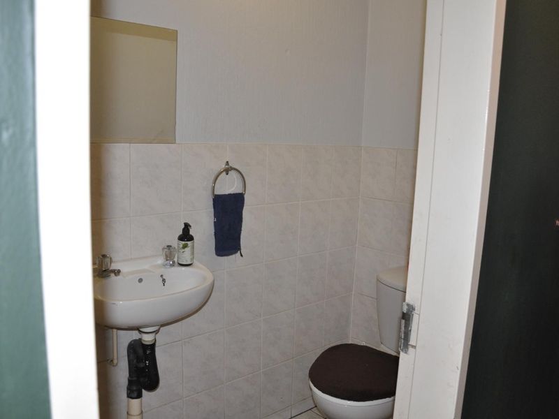A compact guest bathroom featuring a wall-mounted basin and a standard toilet with tiled splashbacks.