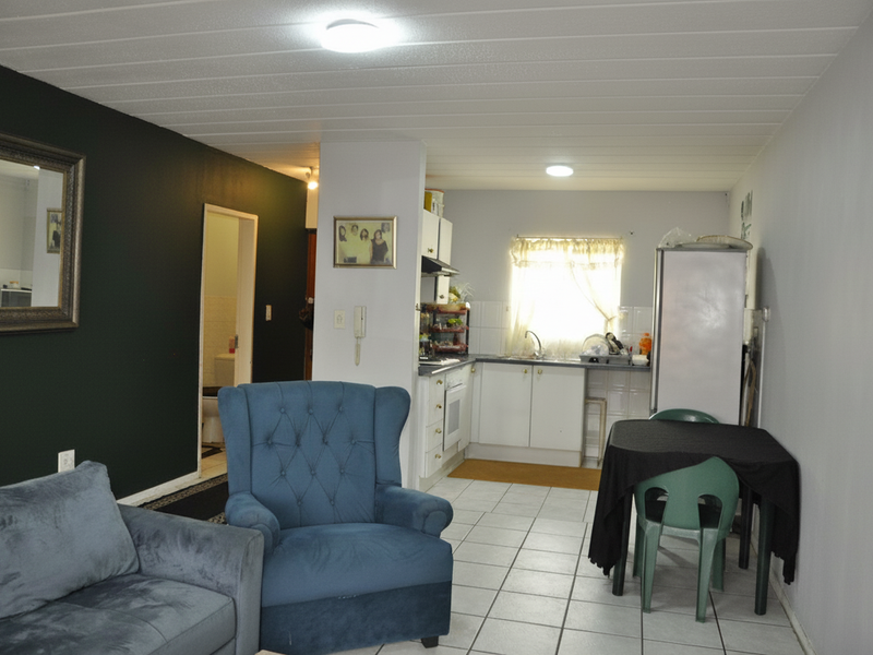 Open plan living and kitchen area featuring tiled flooring, built-in kitchen cabinetry, and a functional layout suitable for modern living.