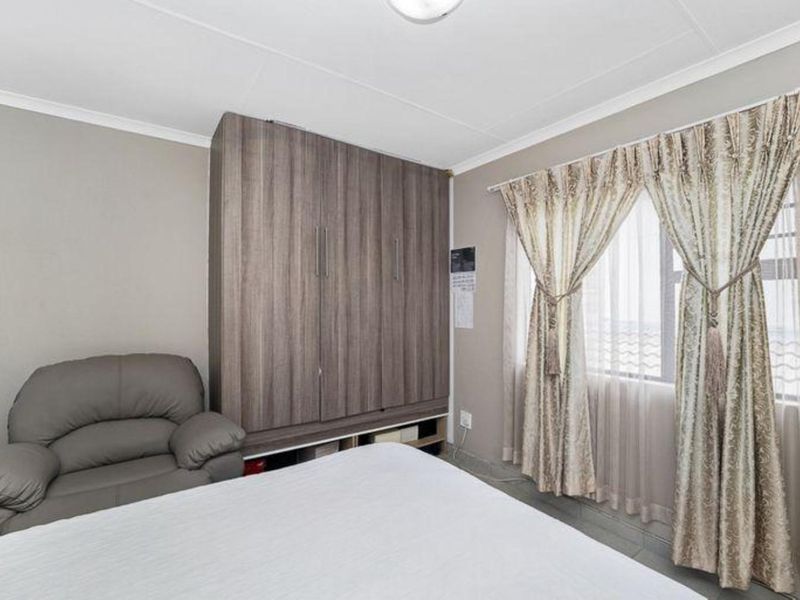 A bedroom featuring built-in wooden cabinetry and a window with curtain treatments.