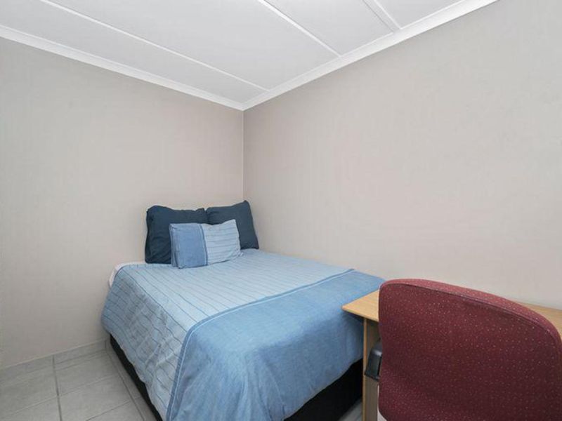 A compact bedroom featuring tiled flooring and built-in cupboard storage.