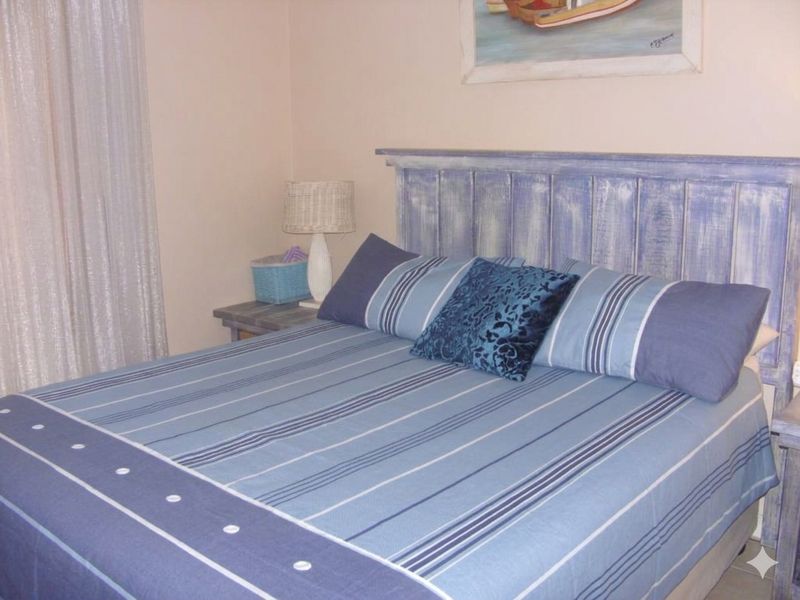 A cozy bedroom featuring a rustic blue wooden headboard and neutral wall finishes.