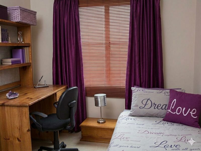 A bedroom featuring tiled flooring, venetian blinds, and curtain rails, providing a functional space for rest or study.