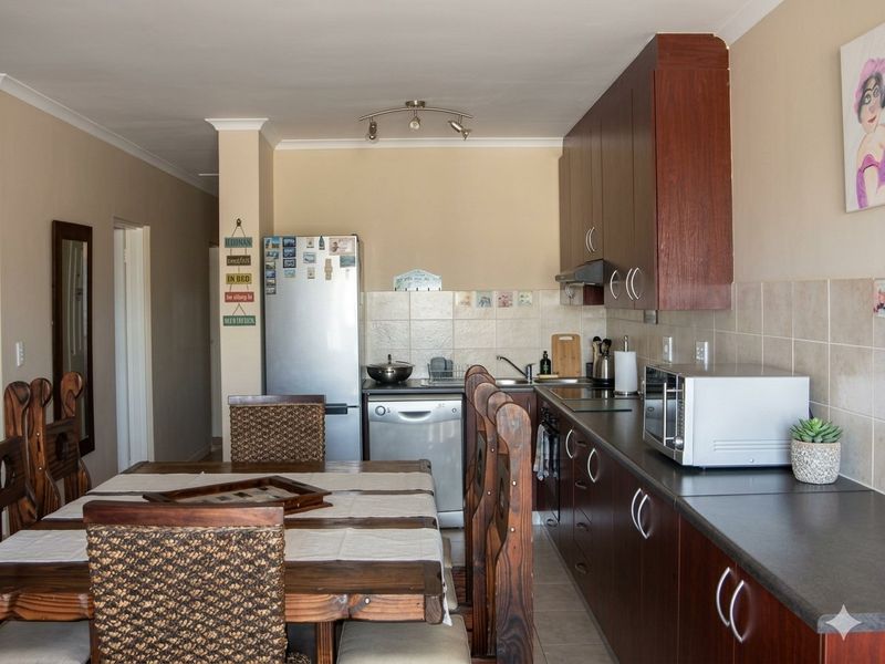 Open-plan kitchen and dining area featuring dark wood cabinetry, laminate countertops, and tiled backsplash, creating a functional and connected living space.