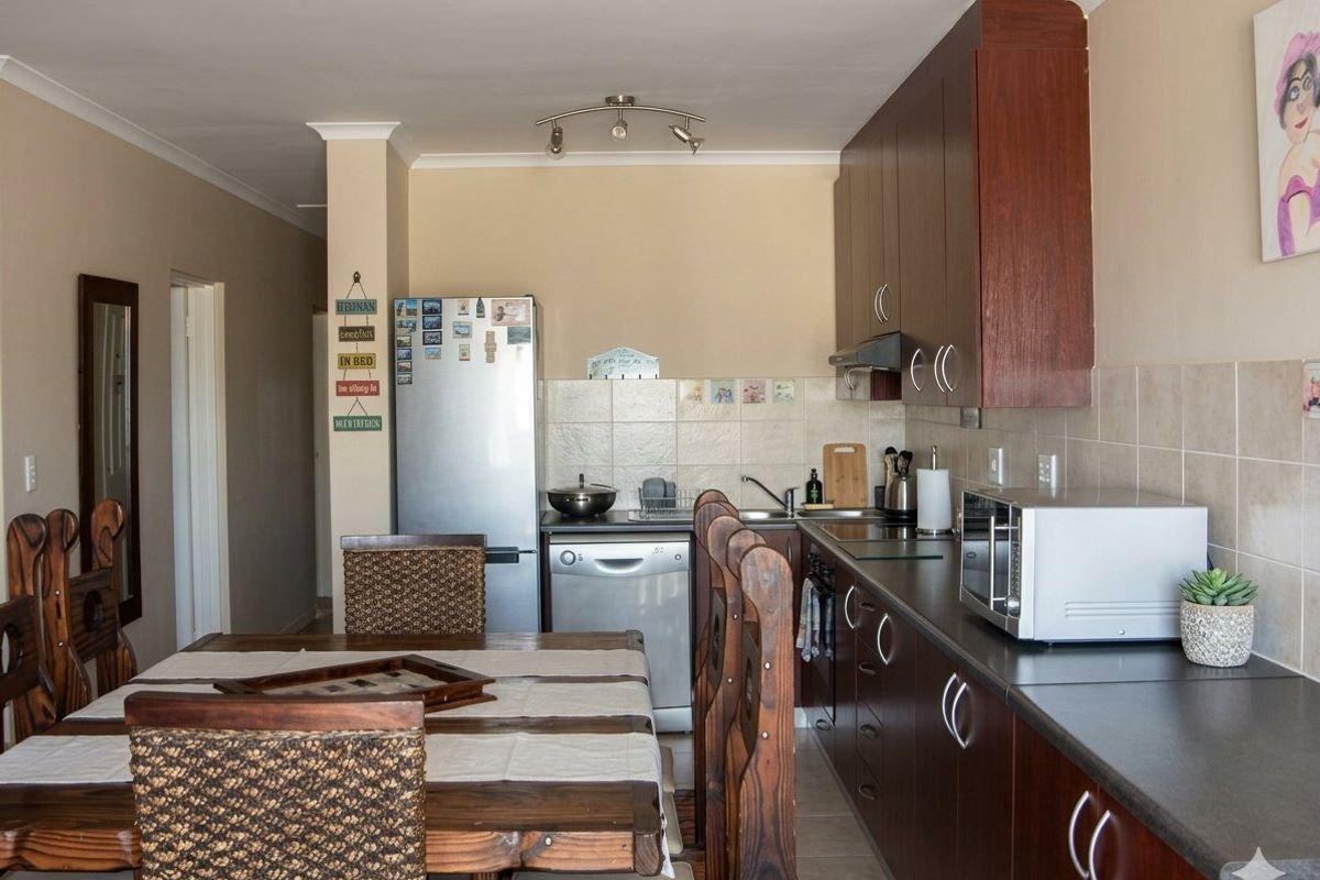Open-plan kitchen and dining area featuring dark wood cabinetry, laminate countertops, and tiled backsplash, creating a functional and connected living space.