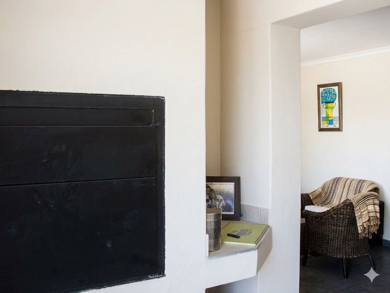 A living area featuring a built-in fireplace with a tiled hearth, leading into an adjacent room.