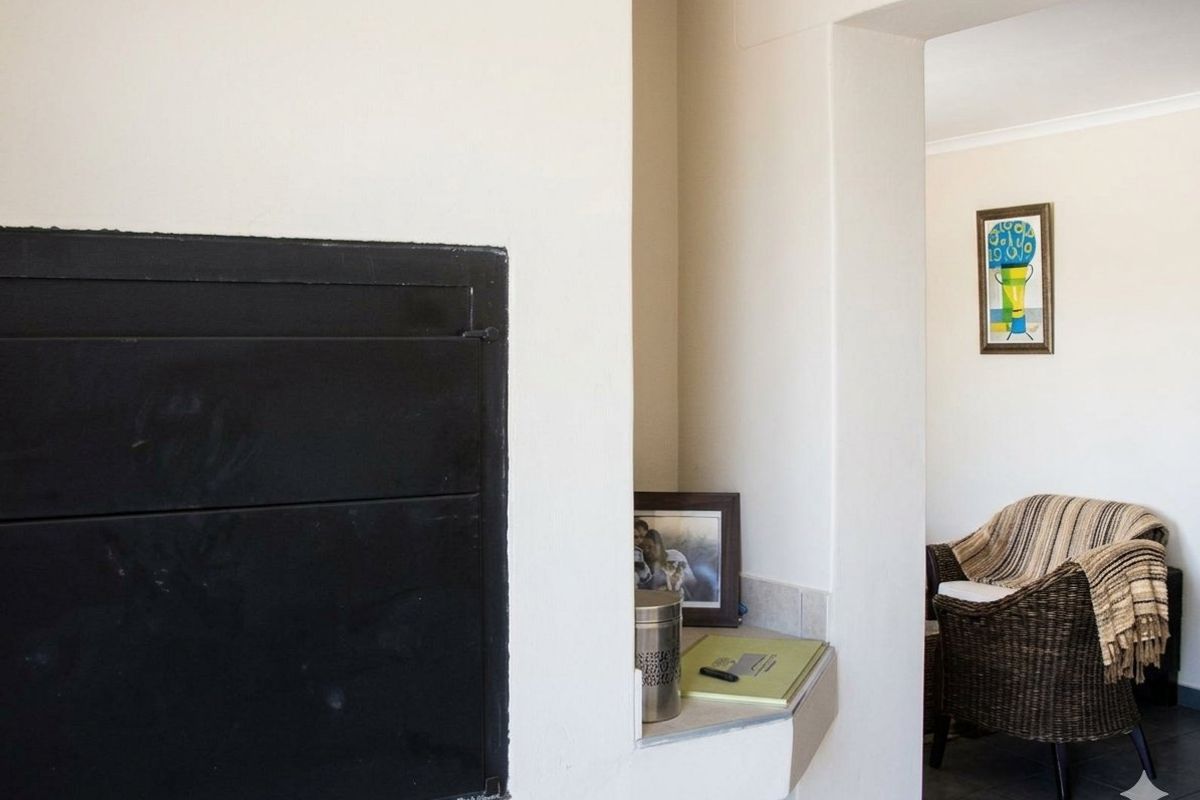 A living area featuring a built-in fireplace with a tiled hearth, leading into an adjacent room.