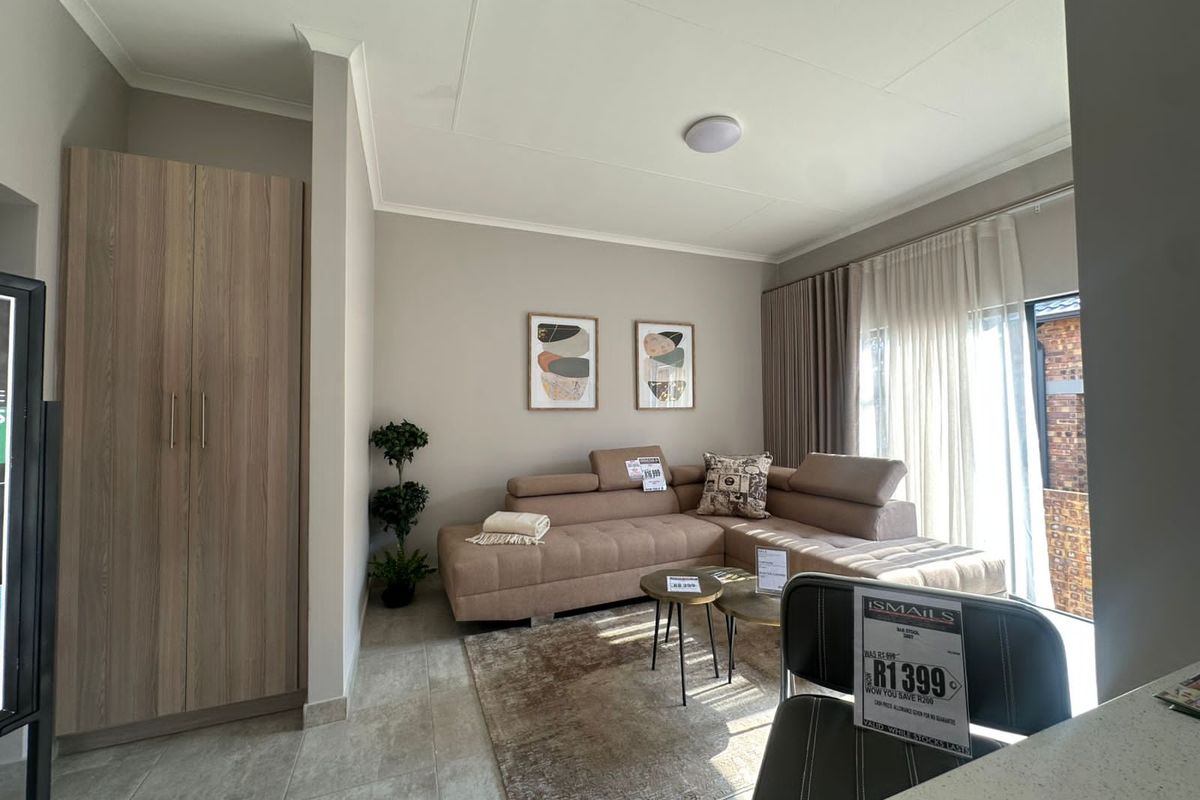 A bright living area featuring neutral wall tones, tiled flooring, and a built-in wooden wardrobe, with direct access to an outdoor space.