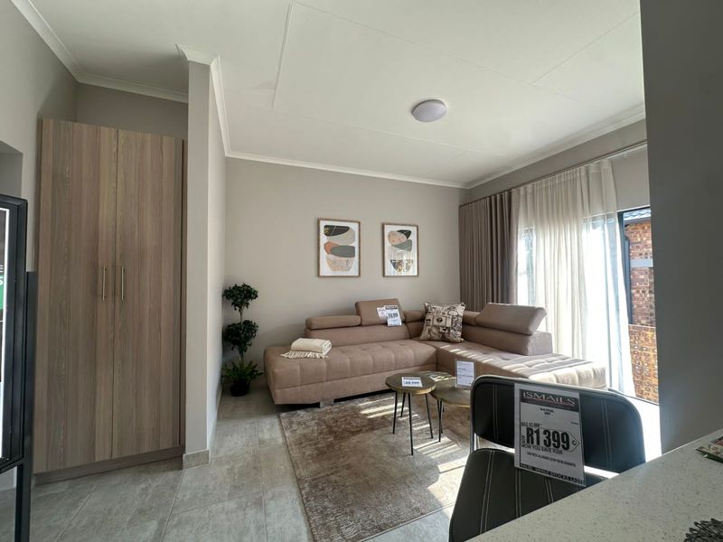 A bright living area featuring neutral wall tones, tiled flooring, and a built-in wooden wardrobe, with direct access to an outdoor space.