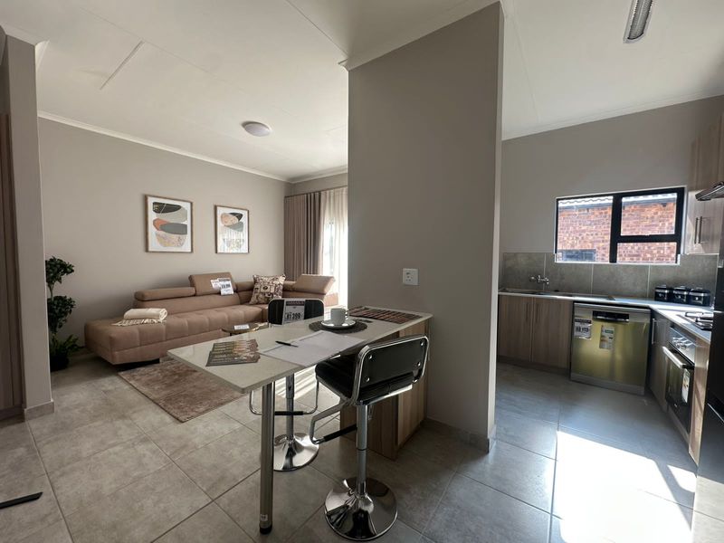 An open-plan living and kitchen area featuring tiled flooring, a breakfast bar, and a functional kitchen layout with built-in cabinetry.