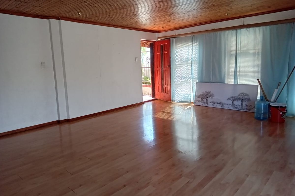 Spacious living area featuring timber ceiling paneling, laminate flooring, and direct access to an outdoor patio through a sliding glass door.